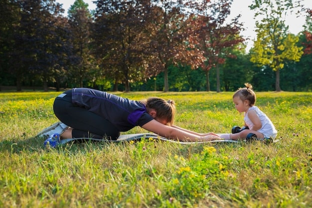 A parent kneels to a child's height, making eye contact and actively listening with a gentle expression. They are outside in a park on a sunny day.