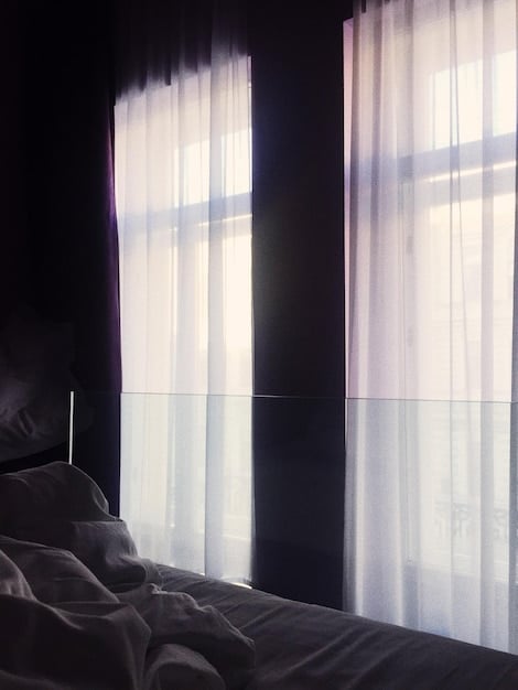 Blackout curtains completely blocking out sunlight in a modern bedroom, emphasizing the darkness and tranquility of the room.