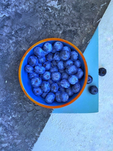 A close-up shot of fresh blueberries in a bowl, highlighting their deep blue color and natural bloom. The image is set against a blurred background to emphasize the berries' appeal and antioxidant-rich properties.