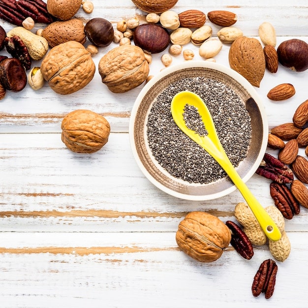 A visually appealing display of various nuts and seeds, including walnuts, almonds, flaxseeds, and chia seeds, arranged in a rustic ceramic bowl. The shot emphasizes the natural textures and earthy tones, highlighting their nutritious value.