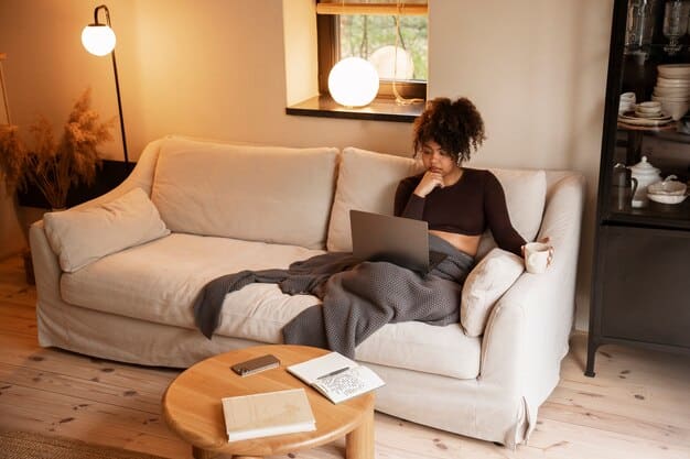 A relaxing living room scene with a comfortable couch, soft lighting, and a bookshelf in the background. A laptop is closed on a nearby coffee table, symbolizing downtime and disconnection from work.