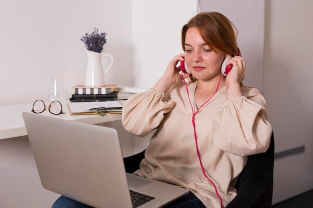 A woman working on her laptop at home, using noise-canceling headphones to reduce distractions, showcasing a focused and productive workspace.