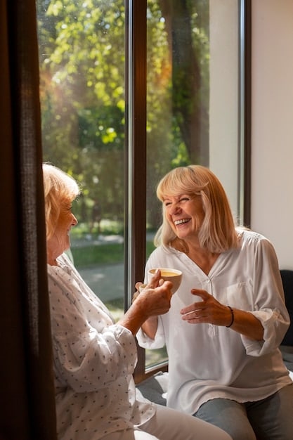 An elderly woman receiving assistance from a home health aide in her living room, with sunlight streaming through the window and creating a warm, comforting atmosphere.