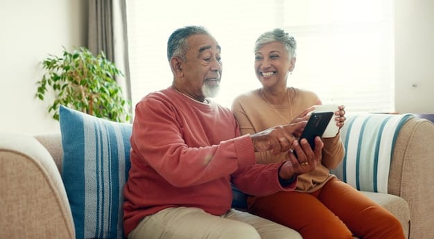 A caregiver assisting a senior in using a mobile app on a tablet for medication reminders while comfortably sitting on a couch in a living room.
